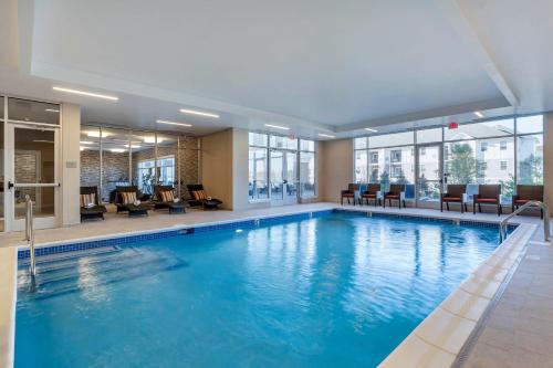 a swimming pool in a hotel with chairs and tables at Cambria Hotel Manchester South Windsor in South Windsor