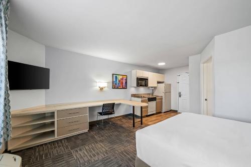 an apartment bedroom with a desk and a kitchen at MainStay Suites Greensboro in Greensboro