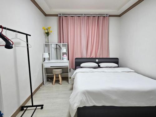 a bedroom with a bed and a desk with a mirror at Gwangalli Tahee House in Busan