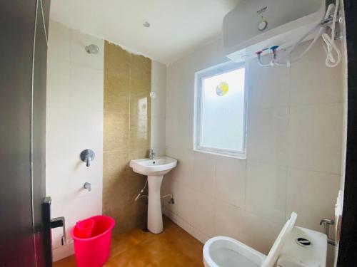 a bathroom with a sink and a toilet and a window at The Warmwood Studio in Dehradun
