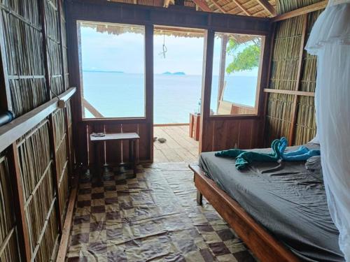 a bedroom with a bed with a view of the ocean at Cozzy Saukabu Homestay in Fam
