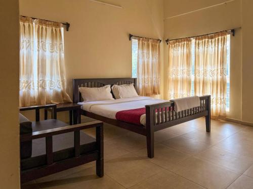 a bedroom with a bed and a window with curtains at The Temple Tree Residence in Yelagiri