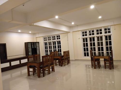 a room with wooden chairs and tables and windows at The Rustic Inn Kaziranga in Kāziranga