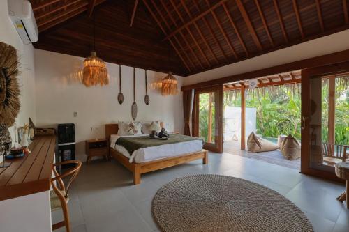 a bedroom with a bed and a table and windows at Bayrin Private Villas in Nusa Penida