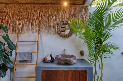 a bathroom with a sink and a palm tree at Bayrin Private Villas in Nusa Penida