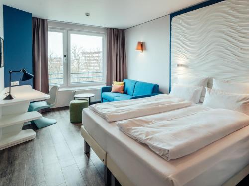 a hotel room with a large bed and a chair at aja Grömitz in Grömitz