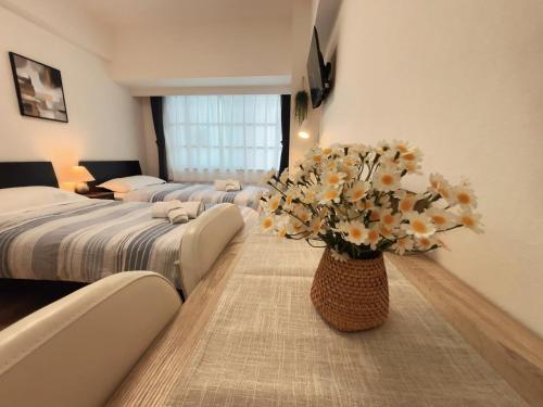 a bedroom with two beds and a vase of flowers at Lucky民泊 in Osaka