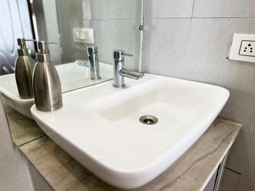 a white sink in a bathroom with a mirror at AtulyaNeer Lakeview Cottage in Kanatal