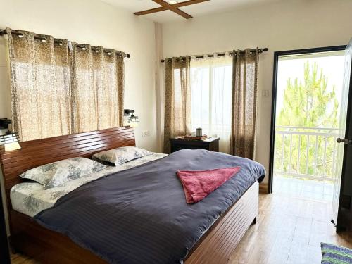 a bedroom with a bed with a red pillow on it at AtulyaNeer Lakeview Cottage in Kanatal
