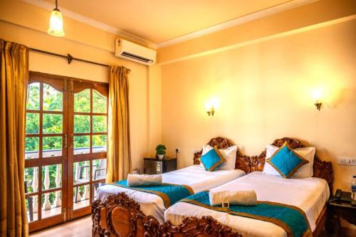 two beds in a room with a window at Hotel Seagull in Calangute