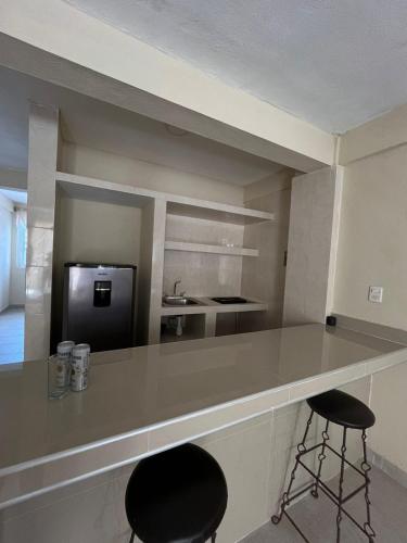 a kitchen with two bar stools and a counter top at Apartamento Turiksa in Acapulco