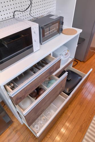 an open drawer in a kitchen with a microwave at Villa上条 名古屋から30分本格ガスグリルでBBQができる宿 in Kasugai