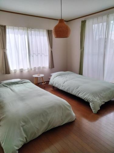two beds in a room with windows at Sakura Inn in Chiba
