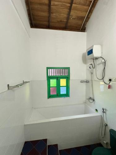 a bath tub in a bathroom with a window at Rella Dream in Matara