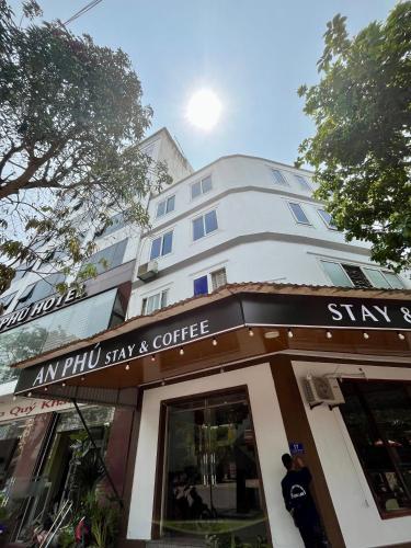 a tall white building with a sign above a coffee shop at An Phú Stay & Coffee in Cửa Lô