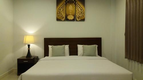 a bedroom with a large white bed and a lamp at Green House Phuket in Ban Pa Khlok