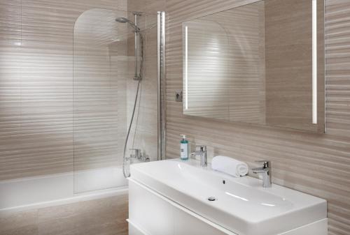 a bathroom with a white sink and a shower at Mamaison Residence Sulekova Bratislava in Bratislava