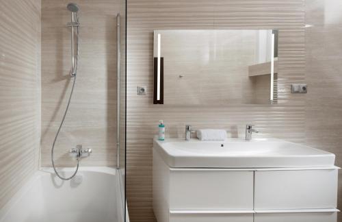 a white bathroom with a sink and a shower at Mamaison Residence Sulekova Bratislava in Bratislava