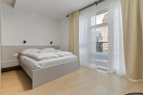 a white bedroom with a bed and a window at LAM Schon - AC in Bratislava