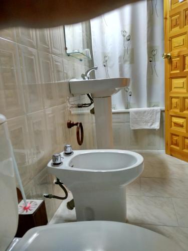 a white bathroom with a sink and a toilet at Pensión Rural Arroyo la Teja in Arroyo Frio