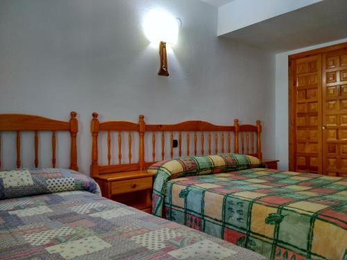 a bedroom with two beds and a light on the wall at Pensión Rural Arroyo la Teja in Arroyo Frio