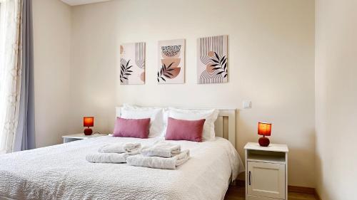 a bedroom with a white bed with pink pillows at Elite 3F Portimão com mar, piscina e garagem in Portimão