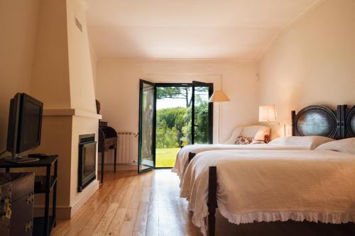 a bedroom with two beds and a tv and a fireplace at Villa Rio Seco in Sintra