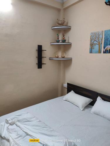 a bedroom with a bed with white sheets and shelves at Uma's Homestay in Gwalior