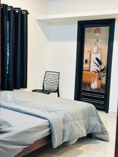 a bedroom with two beds and a chair and a window at Mausam Homestay in Sultan Bathery