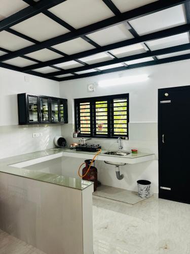 a large white kitchen with a sink and a counter at Mausam Homestay in Sultan Bathery