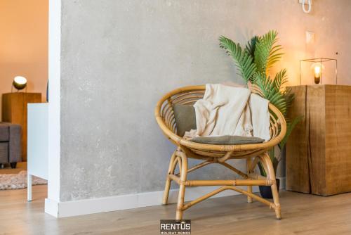 a wicker chair with a pillow in a room at Sandy View - spacious studio flat near the beach in Nieuwpoort