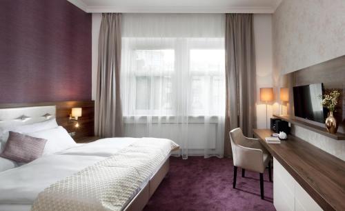 a hotel room with a bed and a desk and a window at Mamaison Residence Sulekova Bratislava in Bratislava