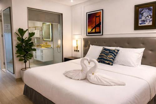 two swans are sitting on a bed in a bedroom at Luxury Studio Infinity Pool Golden Bay in Danang