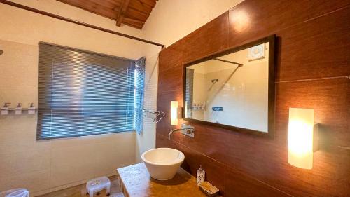 a bathroom with a sink and a mirror on the wall at Natural Elements by Levitate - Premium Two Room Chalet with Private Terrace Panoramic Forest View & Dedicated Kitchen in Rāmgarh
