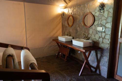 a bathroom with two sinks and two mirrors on the wall at Oreteti Mara Lodge in Lolgorien