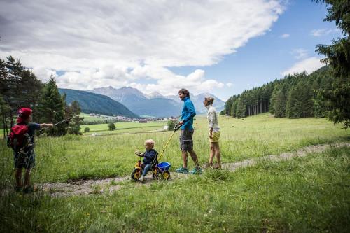 a family standing in a field with a baby in a stroller at Autentis in Rasùn di Sotto