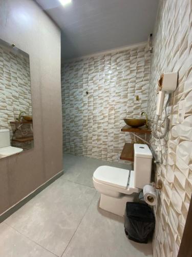 a bathroom with a toilet and a stone wall at Jardim Florestal Italy-Casa Jacarandá in Itaquatiara