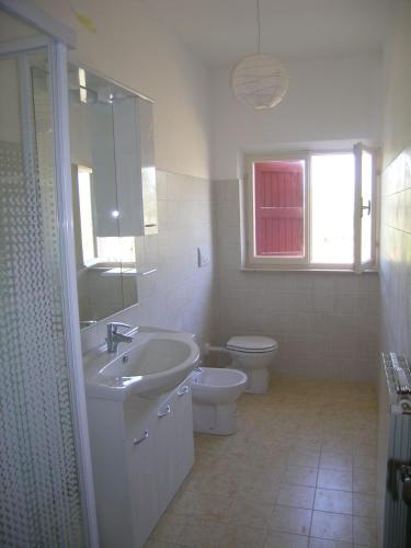 a white bathroom with a sink and a toilet at L'oleandra appartamenti in Lacona