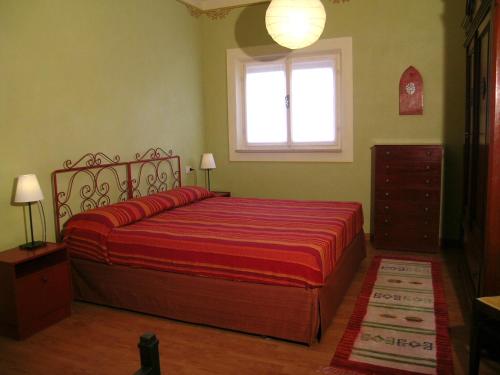 a bedroom with a bed with a red blanket and a window at L'oleandra appartamenti in Lacona