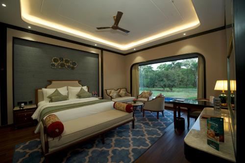 a bedroom with a bed and a desk and a window at Ramada Khajuraho in Khajurāho