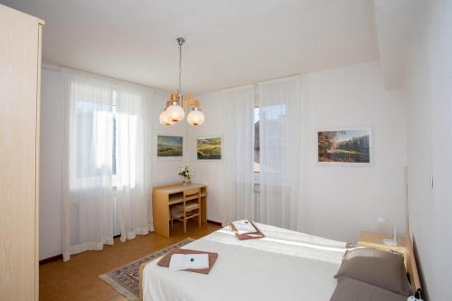 a white bedroom with a bed and a table at ANESI appartamenti in Baselga di Pinè