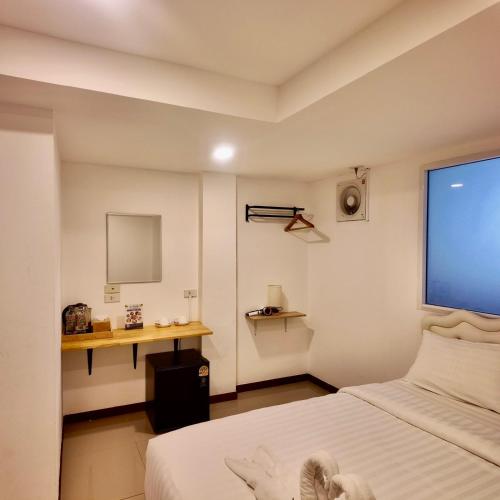 a bedroom with a bed and a desk and a window at Shwe Ooe Lay Guest House 2 in Pratunam