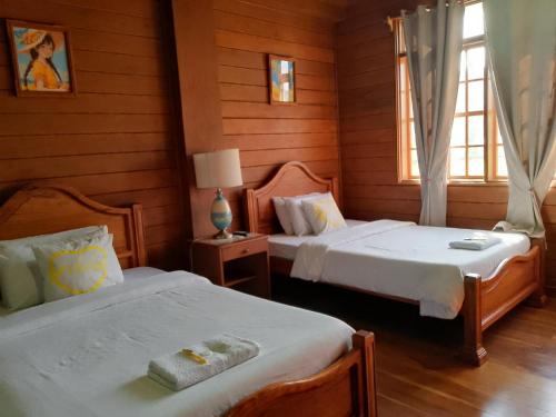 two beds in a room with wooden walls at REKWOOD Hotel in Boracay