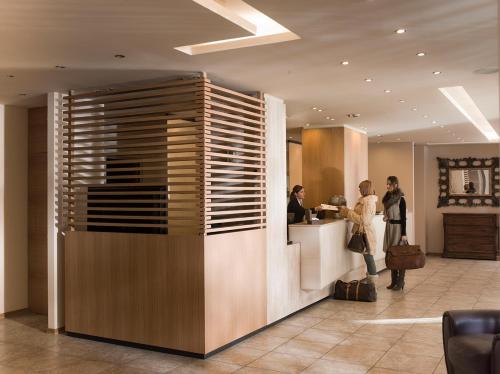 a lobby with people standing at a counter at Grand Hotel Paradiso in Passo del Tonale