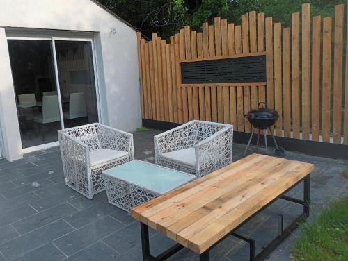a patio with a wooden table and two chairs and a grill at Nature et calme d'Angers in Saint-Martin-du-Fouilloux