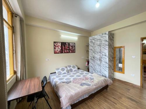 a bedroom with a bed and a table in it at Aangan by Mom in Kalpa