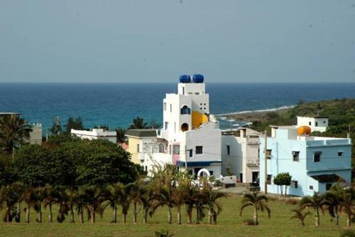 a group of white buildings on a hill near the ocean at Little Path Kenting in Eluan