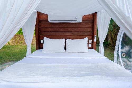 a bed with white sheets and pillows in a tent at Bubble 9 - Luxury Private Pool Experience Ubud in Tampaksiring