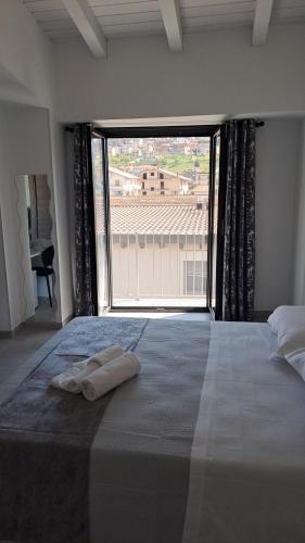 a bedroom with a large window with two towels on a bed at Trilogy b&b in Celano