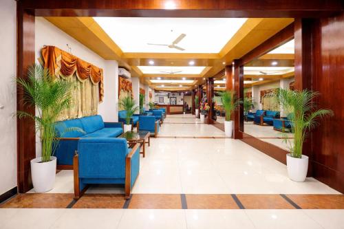 a corridor of a hospital with blue chairs and plants at Hotel Kant Palace in Tājganj